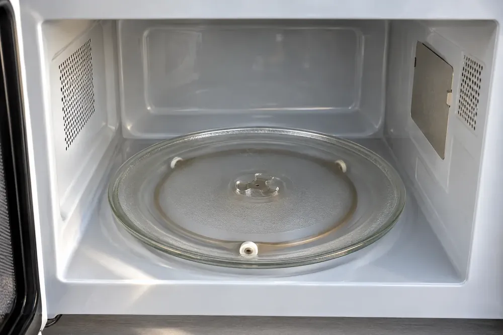 Glass microwave turntable resting on its roller ring beside the clean cavity wall