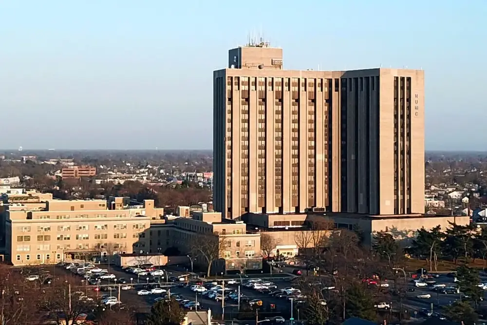 Tall hospital tower rising above low buildings and tree-lined streets in East Meadow, New York