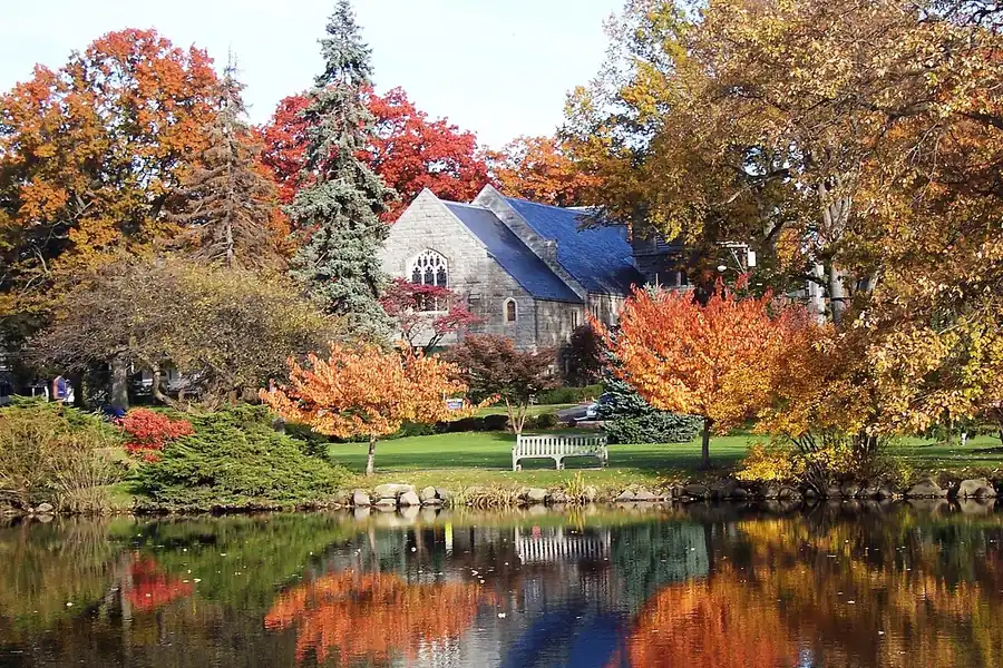 Autumn trees reflected in a pond in front of a church in Greenwich, Connecticut
