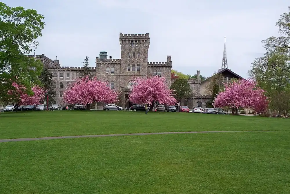 Stone castle building beyond a lawn with blossoming cherry trees in Harrison, New York