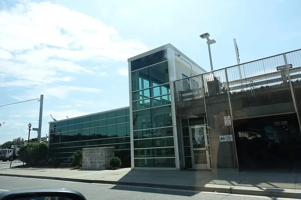 Glass-walled entrance of the elevated Hicksville train station on a sunny day, New York