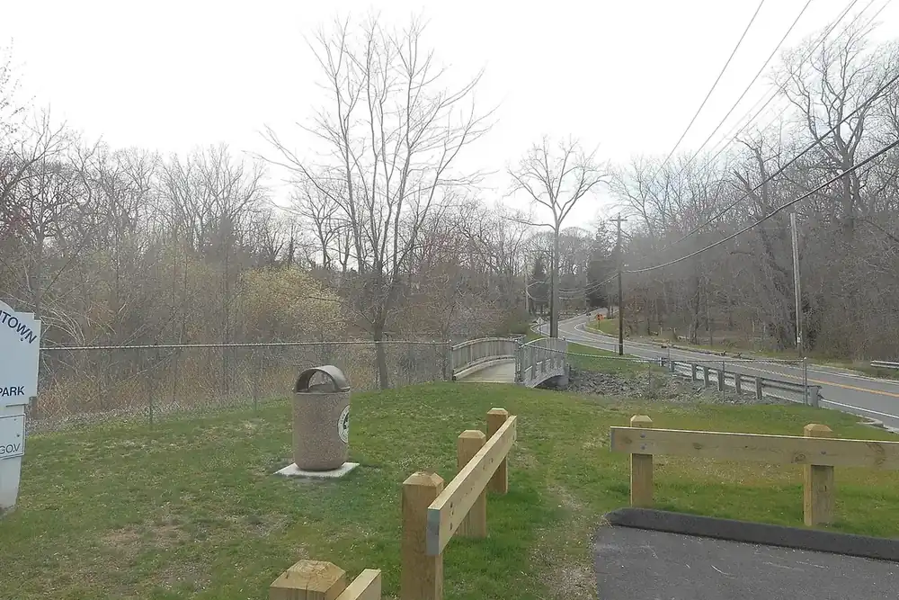 Grassy park slope with a split-rail fence and bare trees in Kings Park, New York