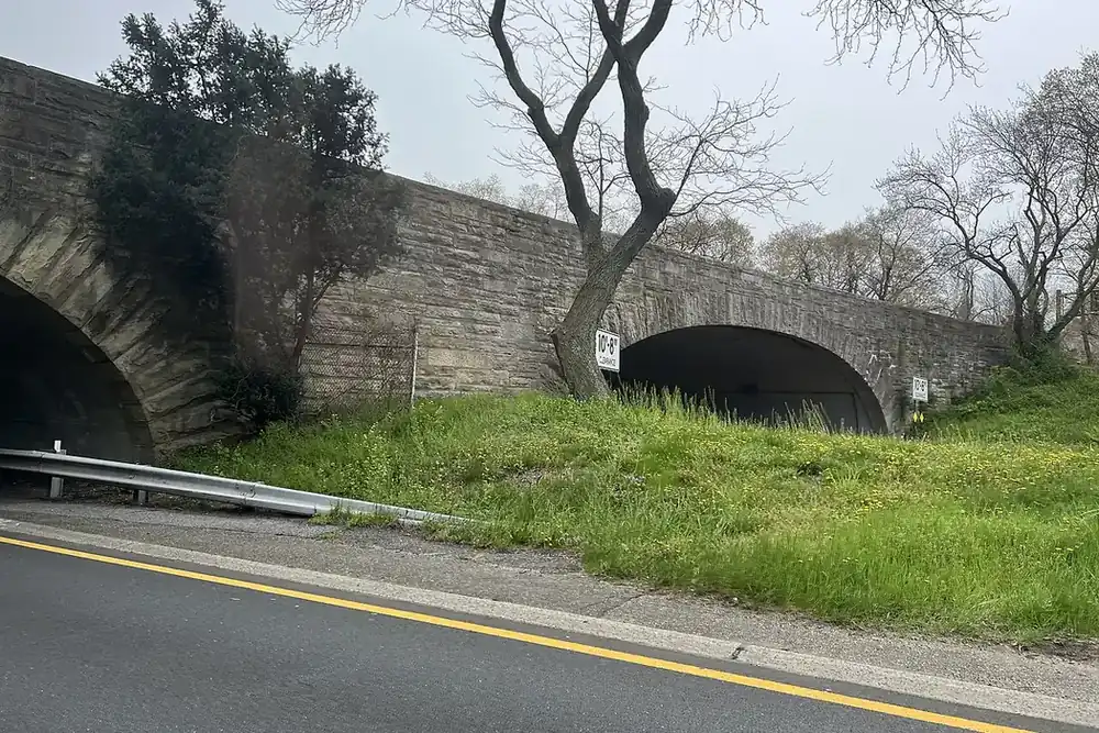 Stone arch bridge over a curving parkway lined with grass and trees near North Massapequa, New York