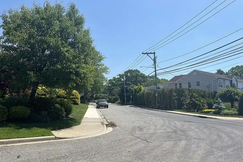 Residential corner with green lawns, shrubs and two-story houses in North Merrick, New York